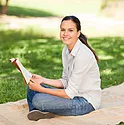 A woman sitting on a blanket reading a book